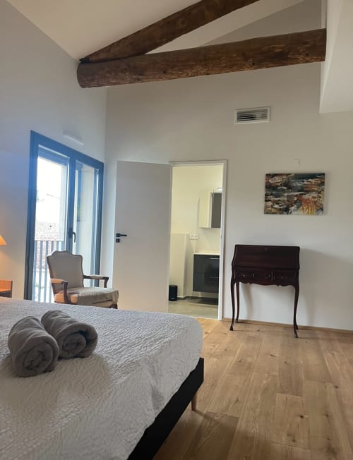 Modern bedroom in Les FOUDRES villa at La Conciergerie De Franck with exposed beams, pool access, and dark wood furnishings