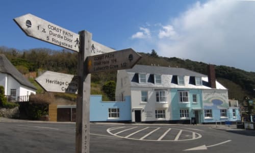 Three Little Pigs hotel in Blandford Forum with directional signpost for Coast Path and local attractions, blue and white