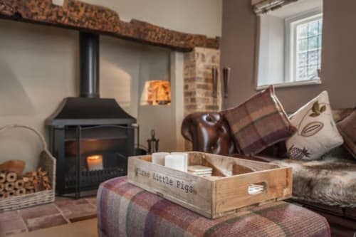 Cozy lounge at Three Little Pigs hotel with wood stove, plaid furnishings, and rustic decor in Blandford Forum