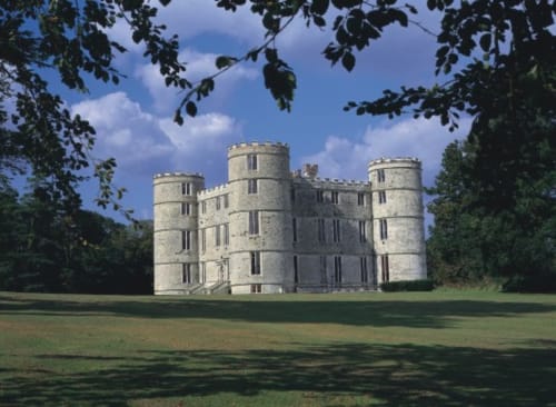 Three Little Pigs castle hotel in Blandford Forum with manicured grounds, cylindrical towers, and blue sky