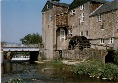 Historic watermill with large wooden wheel on river at Three Little Pigs Hotel, Blandford Forum