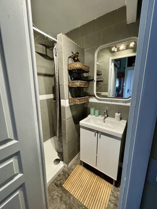 Modern bathroom in Chambre Fleur at Domaine Du Commandeur, Mondragon, with shower, white sink vanity, and woven storage