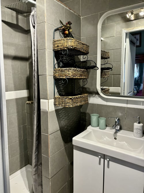 Modern bathroom in Chambre Fleur at Domaine Du Commandeur with woven basket storage, white sink, and shower area