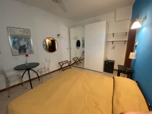 Camera blu di Alloggio Le Casette a Verona con biancheria gialla, specchio rotondo, scrivania e comfort moderni