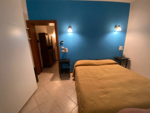 Camera da letto blu presso Alloggio Le Casette a Verona con letto, comodini, applique murali e pavimenti in ceramica