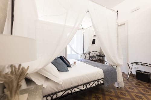 Elegante letto a baldacchino con quattro colonne e drappeggi bianchi nella suite Gli Amanti del B&B I MORI, Catania, con vista sulla città