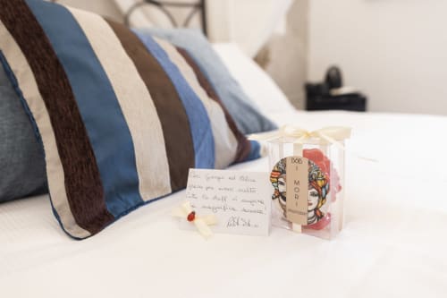 Cuscino rigato con messaggio di benvenuto e prodotti Dolce Vita sul letto dell'hotel boutique I Mori a Catania