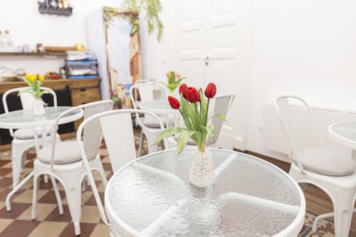 Luminosa sala da pranzo della B&B I MORI a Catania con sedie bianche, tavoli rotondi e tulipani rossi in un vaso