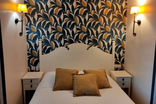 Le Pavillon Saint Martin Hotel double comfort bedroom in Souillac with patterned accent wall, white headboard, and gold