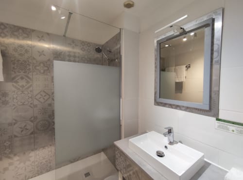Modern bathroom with walk-in shower, white sink, framed mirror at Le Pavillon Saint Martin Hotel, Souillac