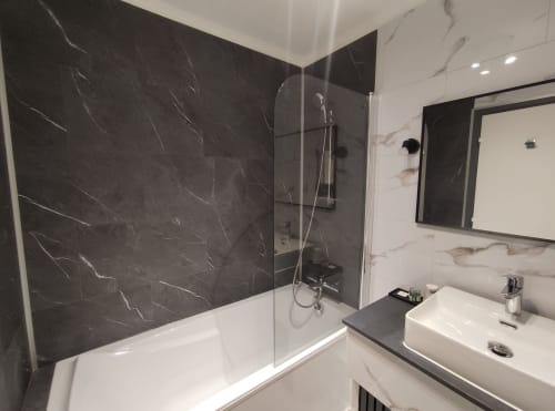 Modern bathroom at Le Pavillon Saint Martin Hotel with dark marble shower, white sink, and mirror in Souillac