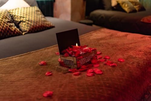 Bougie romantique avec pétales de rose rouge sur table en bois à L'Insolite Spa Privatif, hôtel de luxe à Toulouse