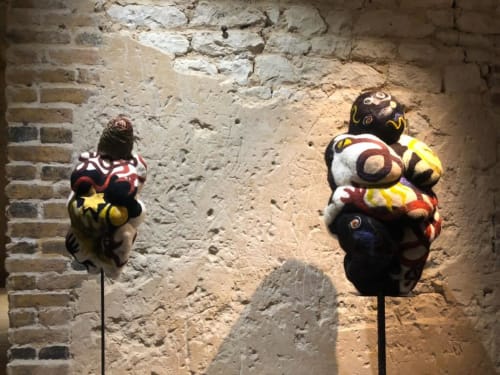 Sculptures décoratives colorées exposées contre un mur de pierre rustique au Domaine de l'Ocrerie à Pourrain
