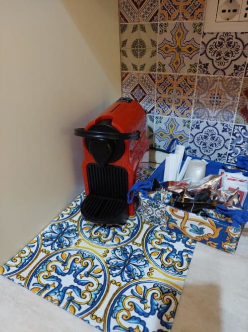 Macchina da caffè rossa su piastrelle decorative siciliane nella cucina dell'appartamento di Cefalù con pavimento a motivi blu e gialli