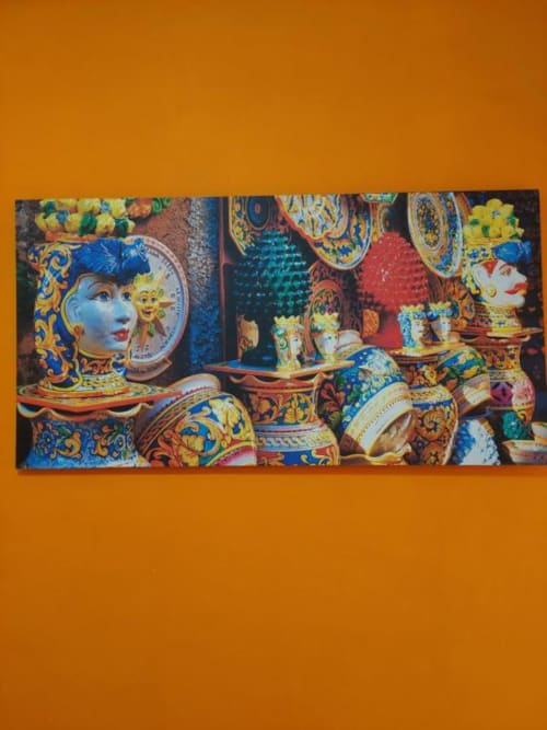 Ceramiche decorative colorate e maschere italiane esposte presso Sikelia House a Cefalù