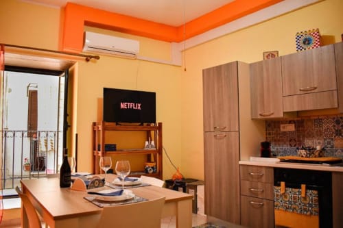 Luminoso appartamento open-plan a Cefalù con accenti arancioni, cucina, zona pranzo, Netflix e accesso al balcone