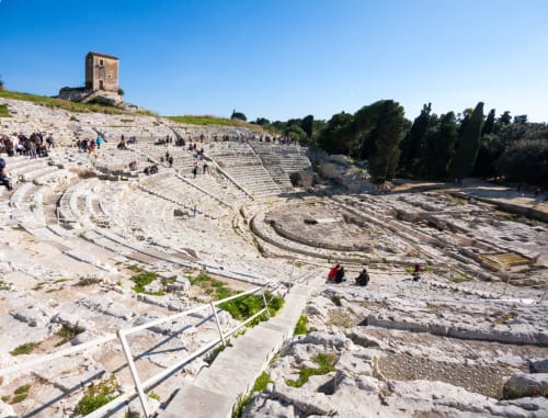 Ancient Greek theater ruins in Agnone Bagni, Italy with curved stone seating and tower structure