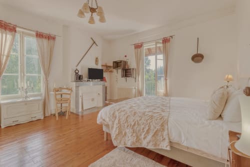 Spacious bedroom at Baccara Lodge in Arengosse with wooden floors, white furnishings, and countryside views