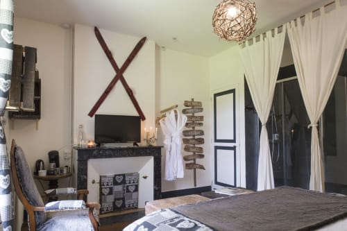 Cozy bedroom at Baccara Lodge B&B in Arengosse with fireplace, white curtains, and rustic decor