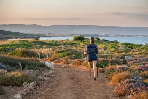 Female runner jogging on coastal trail with sea view at Agnone Bagni, Italy