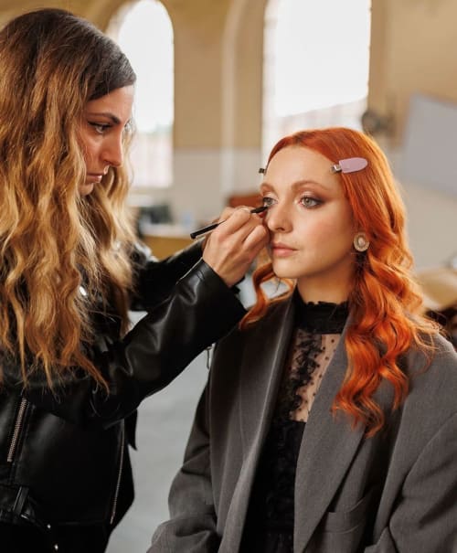 Makeup artist applying eye makeup to woman with red hair at YOUnique Boutique Rooms Milano