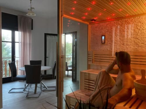 Sauna with red lights and wooden interior at Noemi Holiday House in Agnone Bagni, with sea view apartment visible