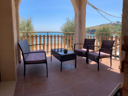 Terrace at Noemi Holiday House with sea views, wicker chairs, and wooden railings overlooking coastal landscape in Agnone