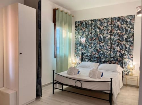 Talìa bedroom at Noemi Holiday House in Agnone Bagni with sea view, featuring black metal bed, floral headboard, and modern