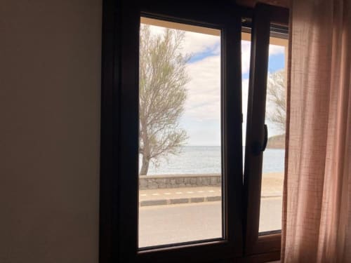 Glass door view from Noemi Holiday House apartment overlooking Adriatic Sea with bare tree and beach in Agnone Bagni