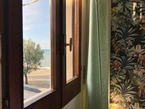 Open door at Noemi Holiday House Talìa apartment revealing sea view, beach, and Mediterranean landscape in Agnone Bagni