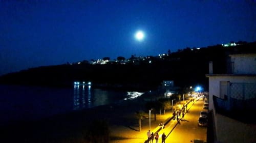 Moonlit coastal promenade at Noemi Holiday House with illuminated seafront path, sea view, and hillside lights in Agnone