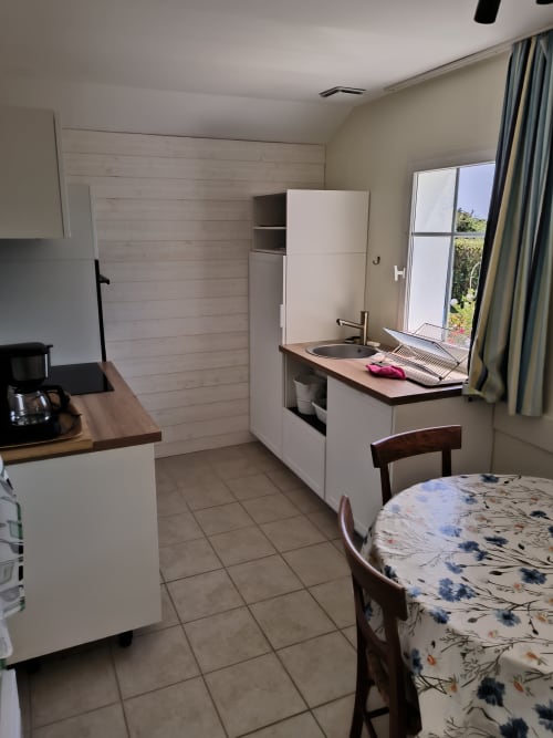 Cuisine et salle à manger modernes de l'appartement Belle Île avec armoires blanches, évier et vue sur la mer