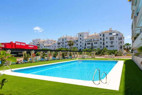 Resort pool with loungers and white apartment buildings in Marbella, Puerto Banús, Spain