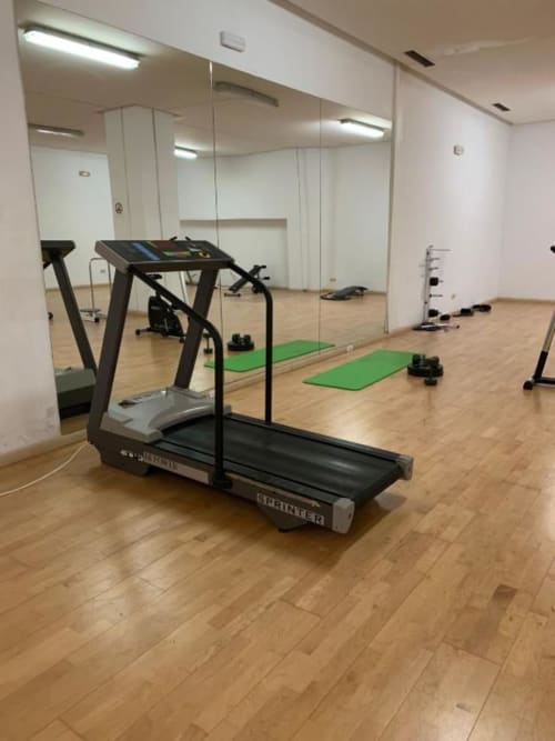 Modern fitness studio at Marbella Home Rentals with treadmill, yoga mats, dumbbells, and mirrored walls