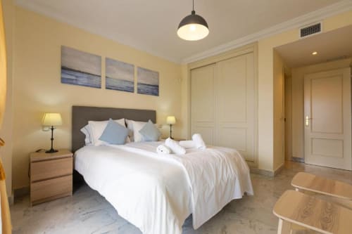 Bright master bedroom at Marbella Home Rentals Puerto Banús apartment with queen bed, nightstands, and modern amenities