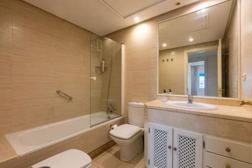 Modern bathroom in Marbella Home Rentals apartment with vanity, toilet, and glass-enclosed shower in Puerto Banús