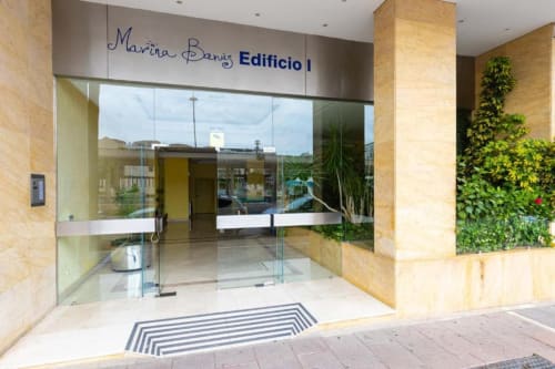 Marina Banús Edificio 1 entrance in Puerto Banús, Marbella - modern apartment building with glass doors and green wall