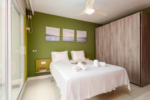 Modern bedroom with green walls, white bed, and wood-grain wardrobe at Marbella Home Rentals, Puerto Banús apartment