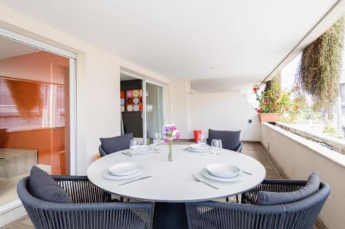 Modern dining terrace at Tembo apartment in Puerto Banús, Marbella with round table, city views and hanging plants