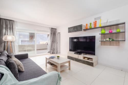 Modern living room in Marbella apartment with TV, sofa, coffee table, and balcony terrace overlooking city