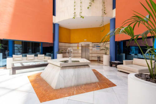 Modern lobby with colorful walls, contemporary furniture, and central water feature at Marbella Home Rentals, Puerto Banús