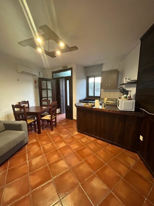 Cocina-comedor de planta abierta con azulejos de barro, muebles de madera oscura y ventilador de techo tipo avión en Mérida