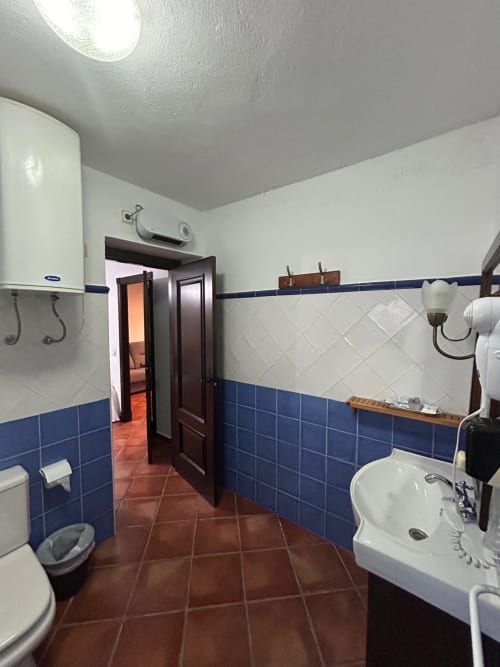 Baño espacioso en el apartamento Gestyp-AT en Mérida con paredes de azulejos azules y blancos, piso de barro, lavabo e inodoro