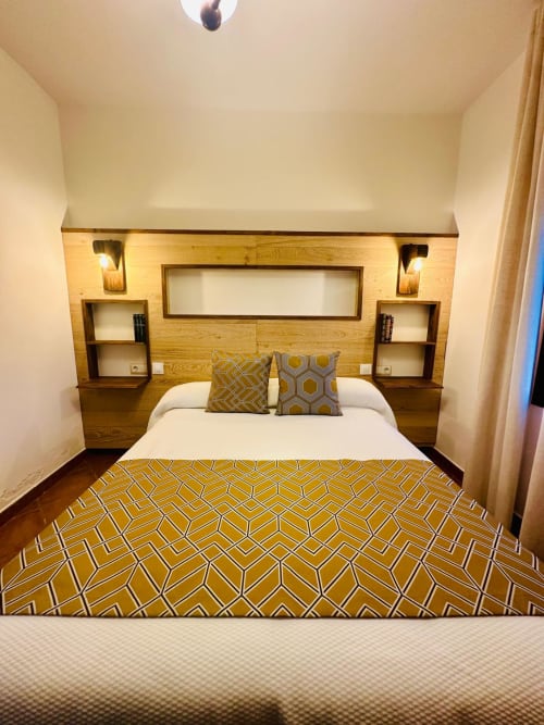 Dormitorio moderno en apartamento Gestyp-AT en Mérida con cabecero de madera, ropa de cama con patrón geométrico e iluminación ambiental