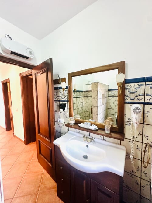 Baño de apartamento en Mérida con tocador de madera, espejo grande, azulejos decorativos y vistas a las montañas desde la ventana