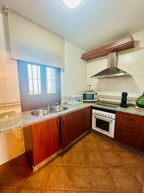 Cocina moderna en apartamento Gestyp-AT, Mérida, con gabinetes rojos, encimeras de granito, electrodomésticos de acero inoxidable y vistas a la montaña