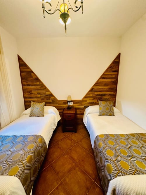 Dormitorio doble en apartamento Gestyp-AT en Mérida con cabeceros de madera y ropa de cama con patrón geométrico