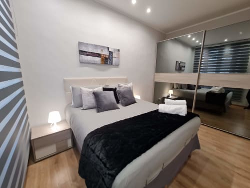 Camera moderna dell'appartamento Raymihome a Torino con letto queen, armadio a specchio, parete a righe e illuminazione d'ambiente