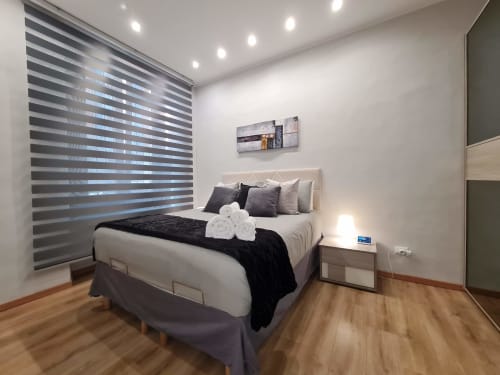 Moderna spavaća soba u apartmanu Raymihome Torino s bračnim krevetom, prugastim roletama, ugrađenim osvjetljenjem i drvenom podlogom
