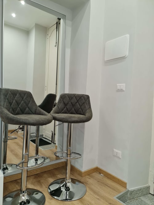 Moderan dnevni boravak u Raymihome Turin s sivim prešivanim barinskim stolicama, zrcalom i drvenim podom